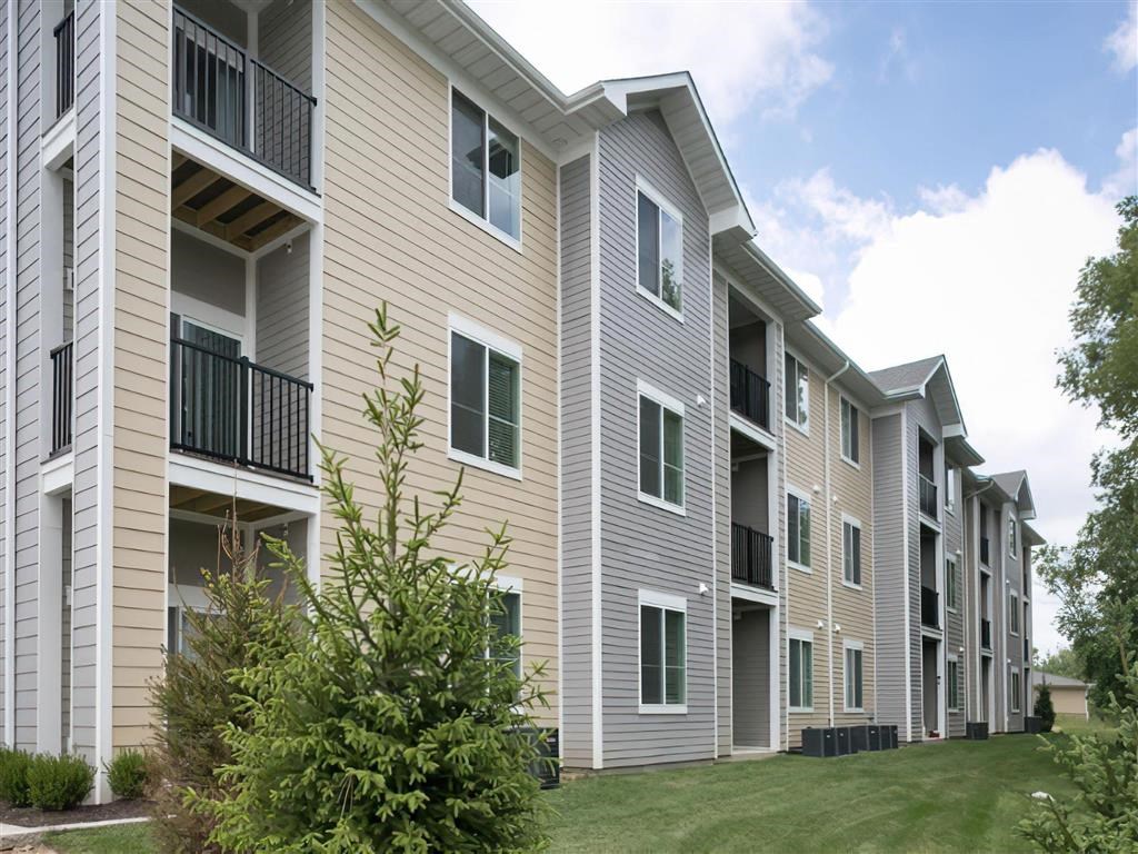 an exterior view of an apartment building with grass