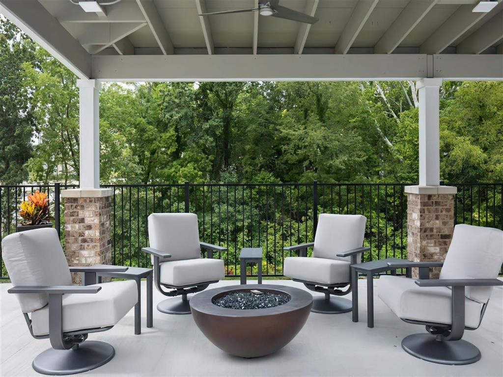 a patio with chairs and tables and a fire pit