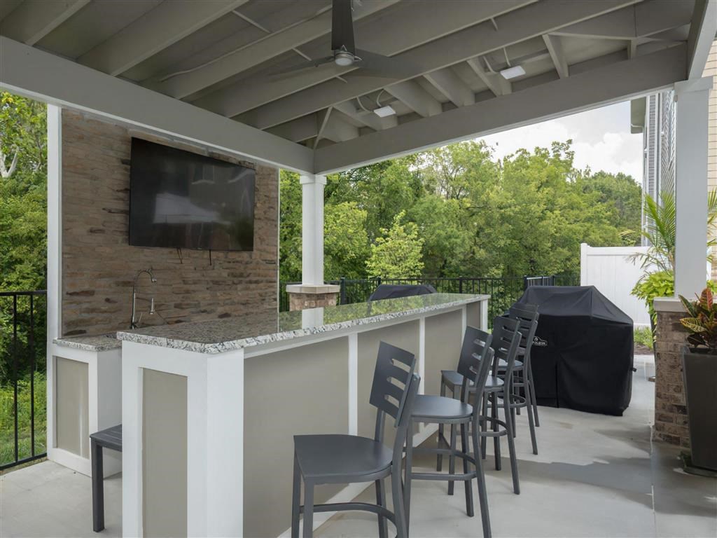 a bar with chairs and a television on a patio