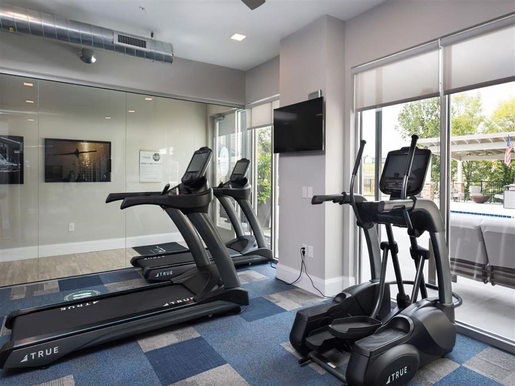 a gym with treadmills and a tv in the corner