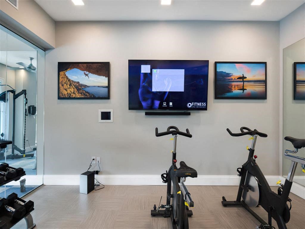 a home gym with exercise bikes and televisions on the wall