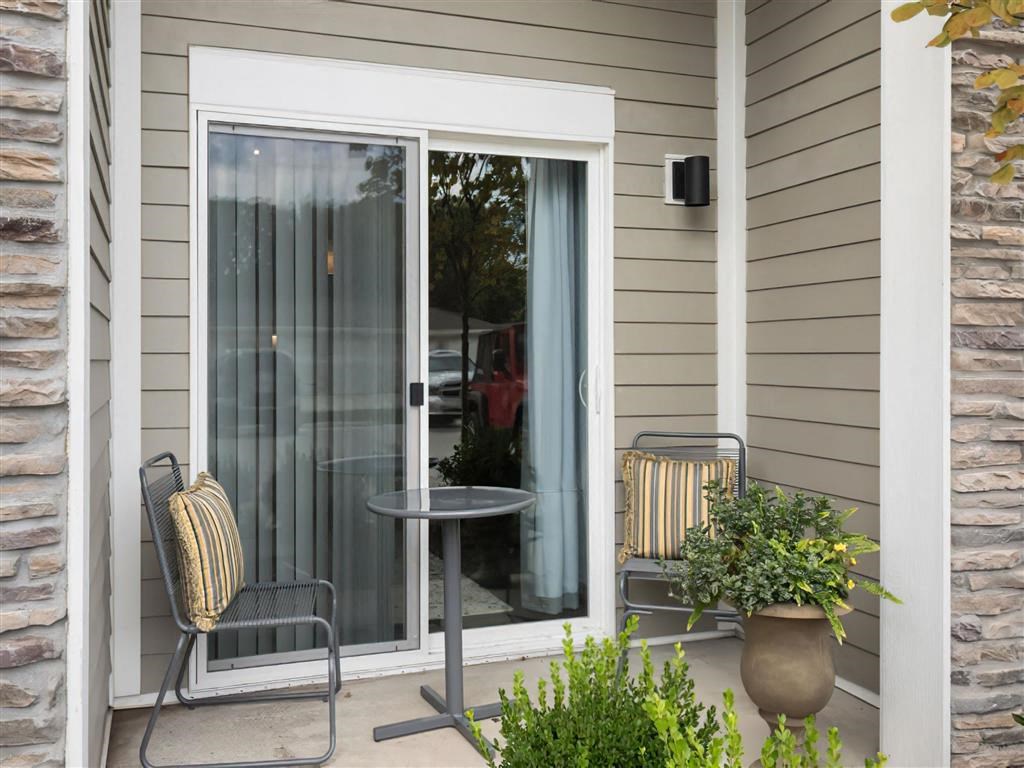 a patio with two chairs and a table in front of a window