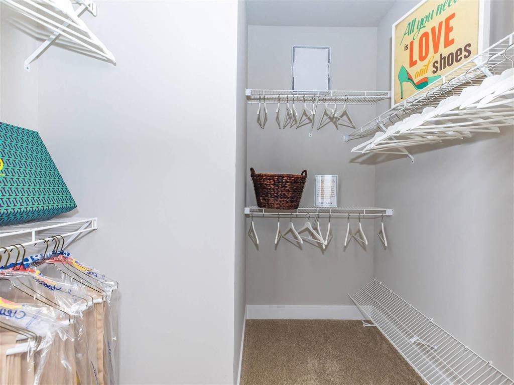 a walk in closet with a door to a closet filled with clothes