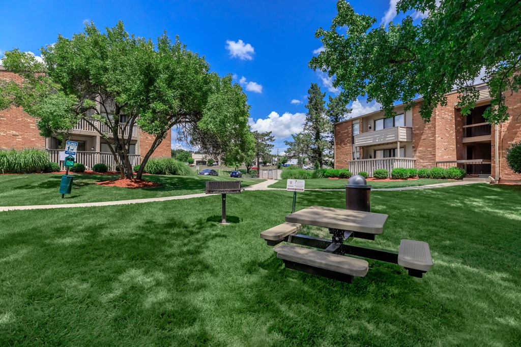 a picnic table in the grass outside of an apartment building