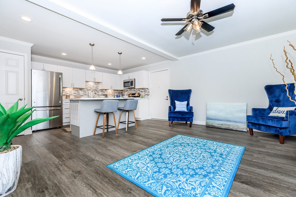 a living room with a kitchen and a ceiling fan