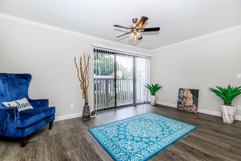 a living room with a blue chair and a ceiling fan