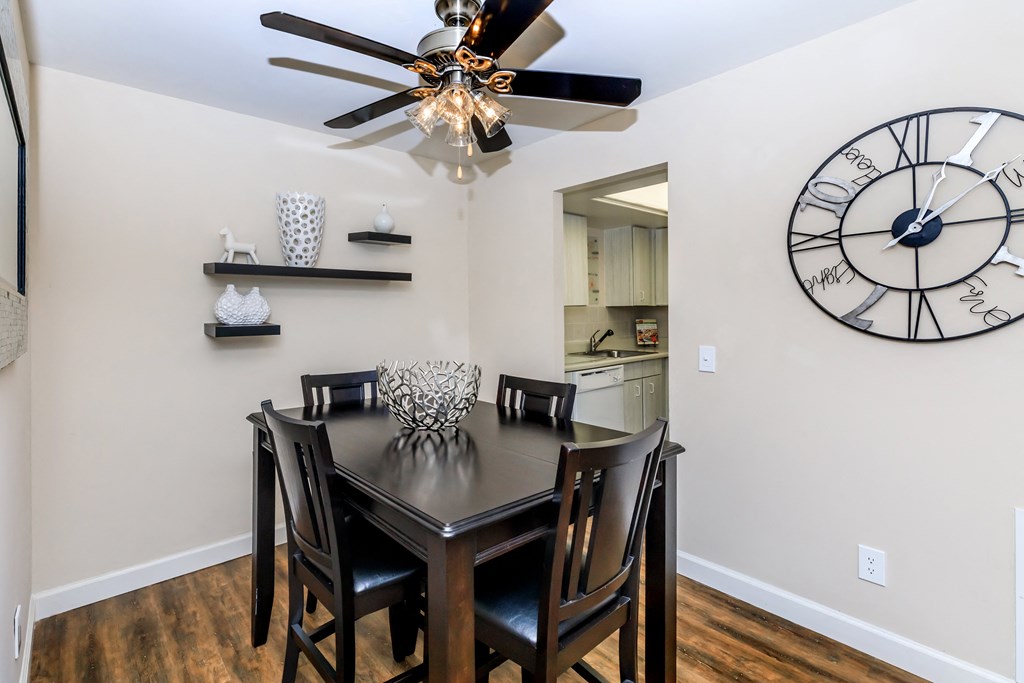 a dining room with a table and chairs and a large clock on the wall