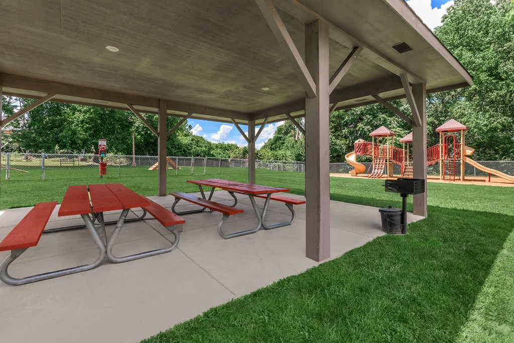 a picnic pavilion with picnic tables in front of a playground