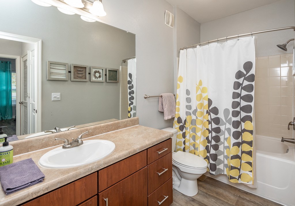 A bathroom with a white sink, a toilet, and a shower curtain with yellow and grey circles.