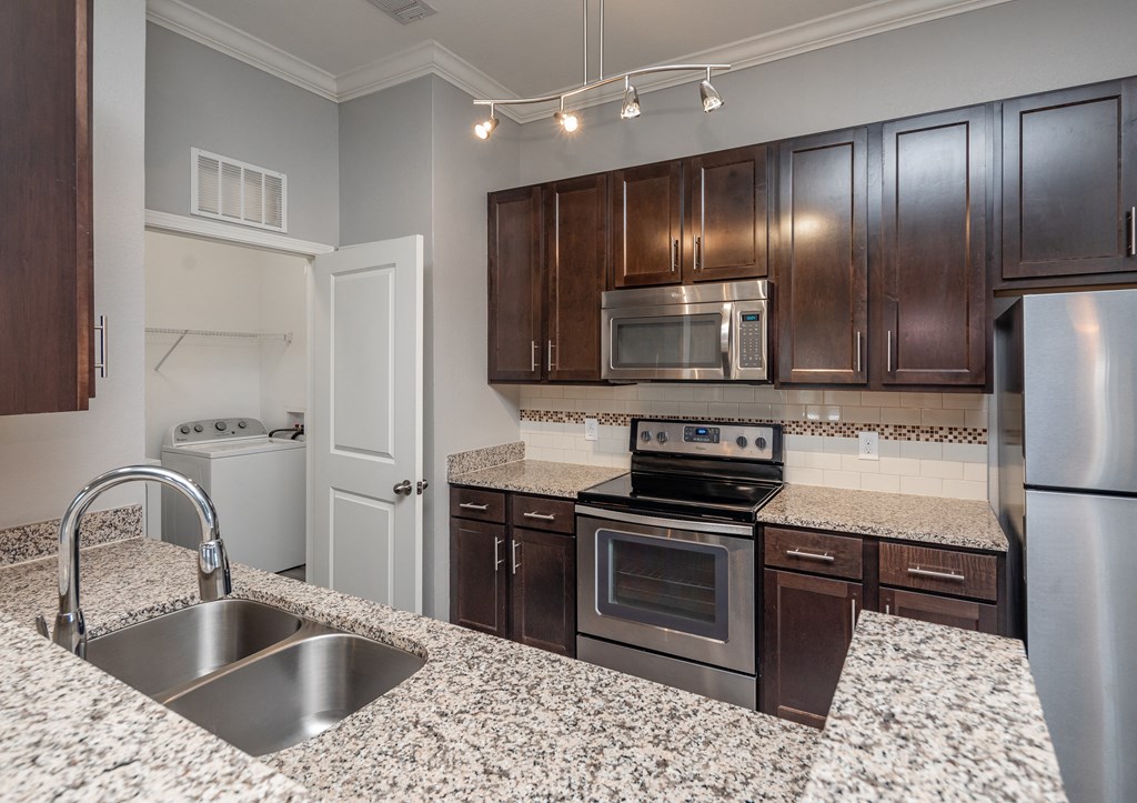 A kitchen with a granite countertop and stainless steel appliances.