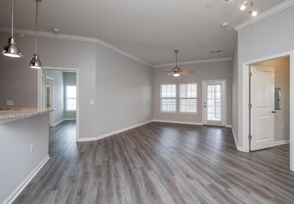 A spacious room with a ceiling fan and hardwood flooring.