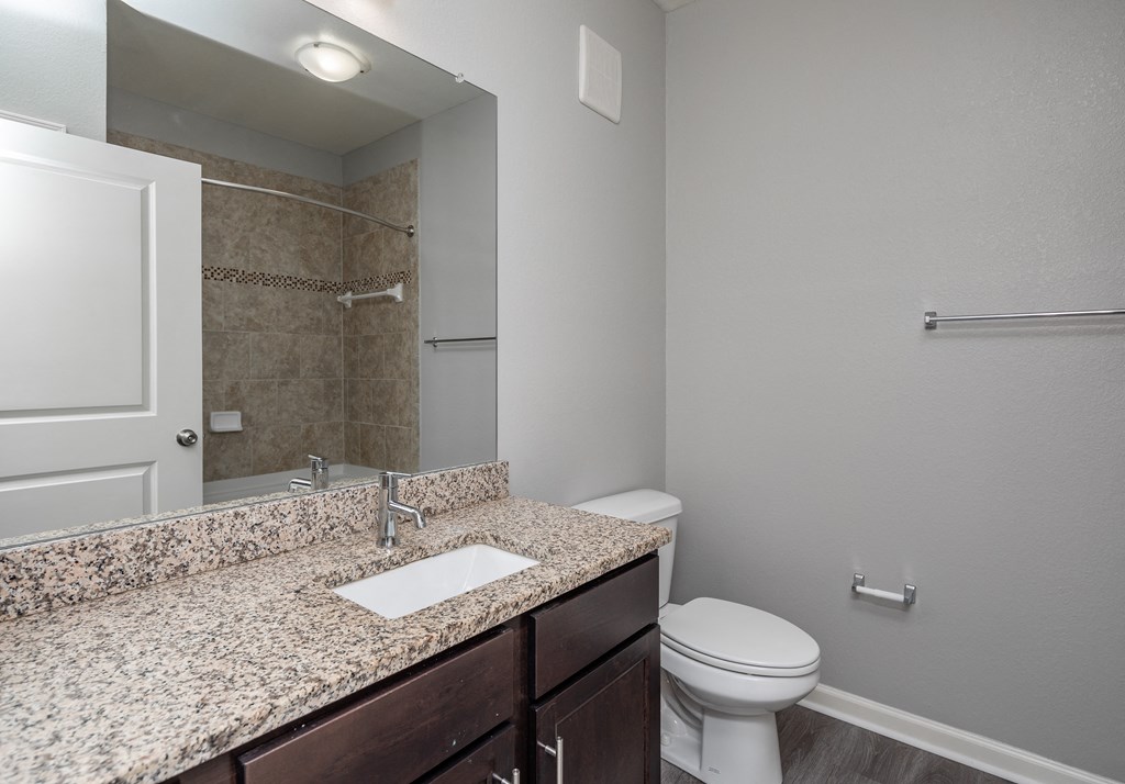 A bathroom with a granite countertop and white toilet.
