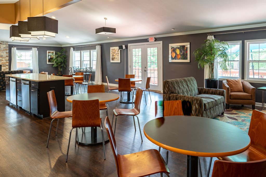 a communal area with tables and chairs and a kitchen and living room