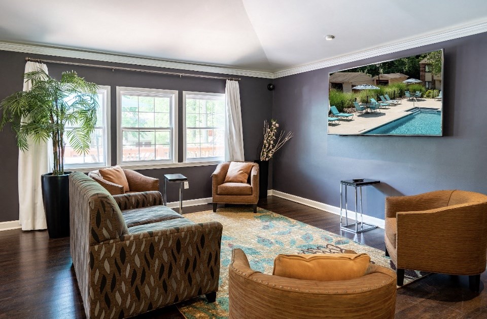 a living room with couches and chairs and a picture of a swimming pool