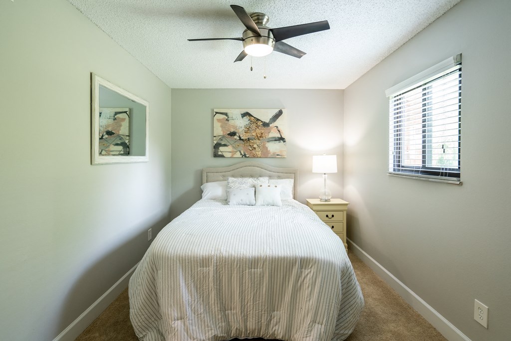 a bedroom with a large white bed and a ceiling fan
