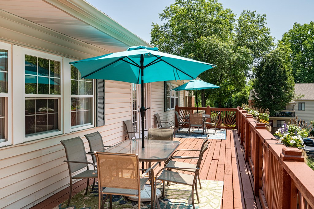 a wooden deck with a table and chairs and umbrellas