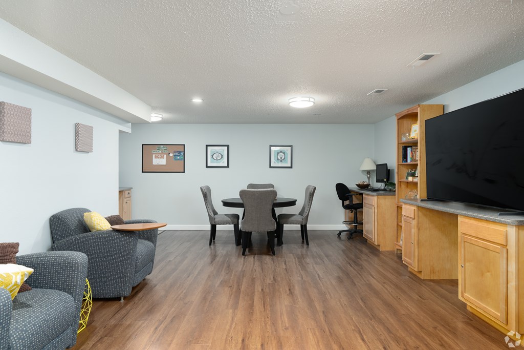 A living room with a grey couch, a black chair, a wooden cabinet, and a television.