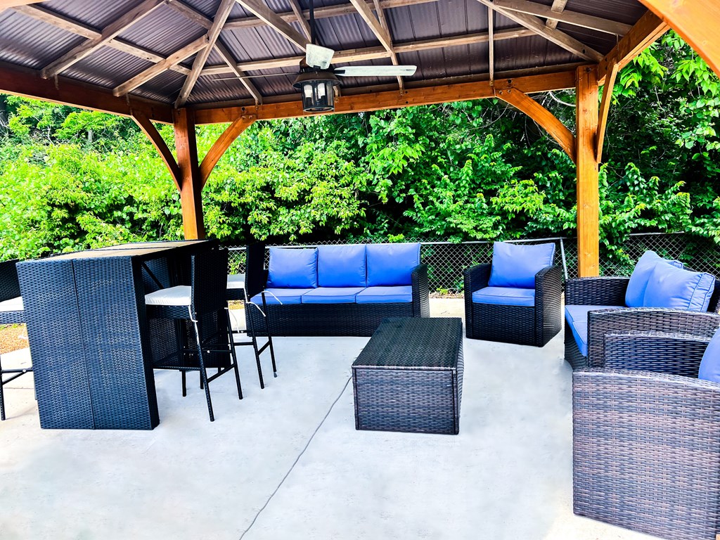 A patio with a black wicker sofa and chairs.