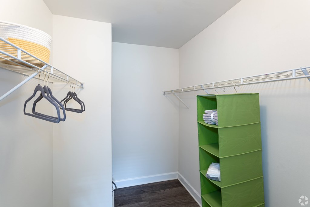A white closet with a green shelf and clothes hanging on a rail.