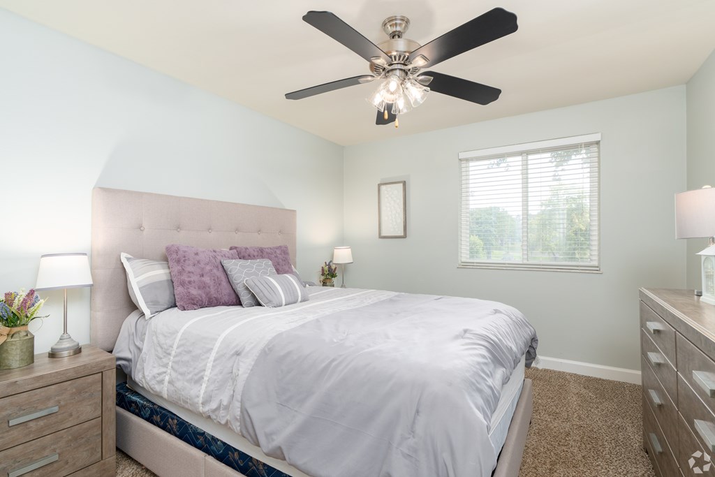 A bedroom with a bed, nightstands, and a ceiling fan.