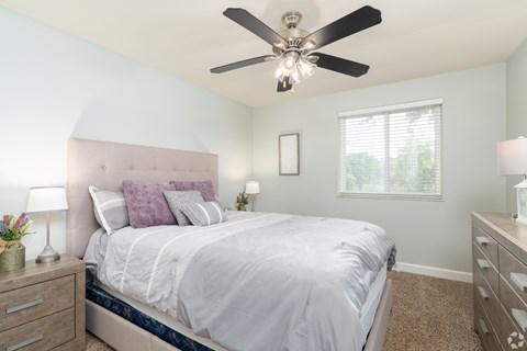 A bedroom with a bed, nightstands, and a ceiling fan.