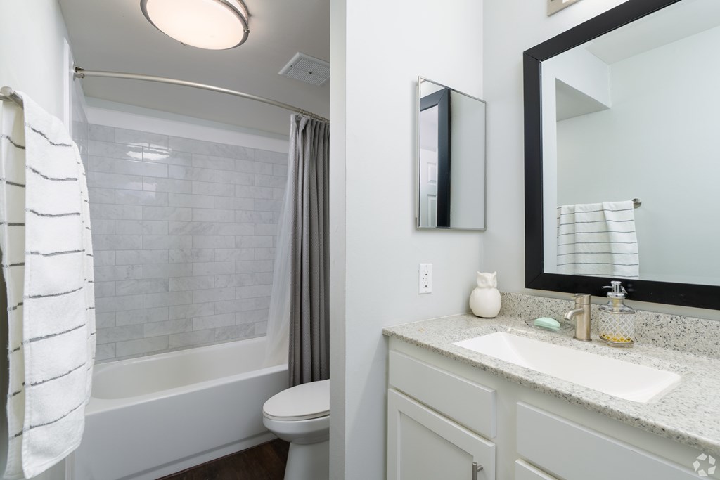 A white bathroom with a toilet, sink, and mirror.
