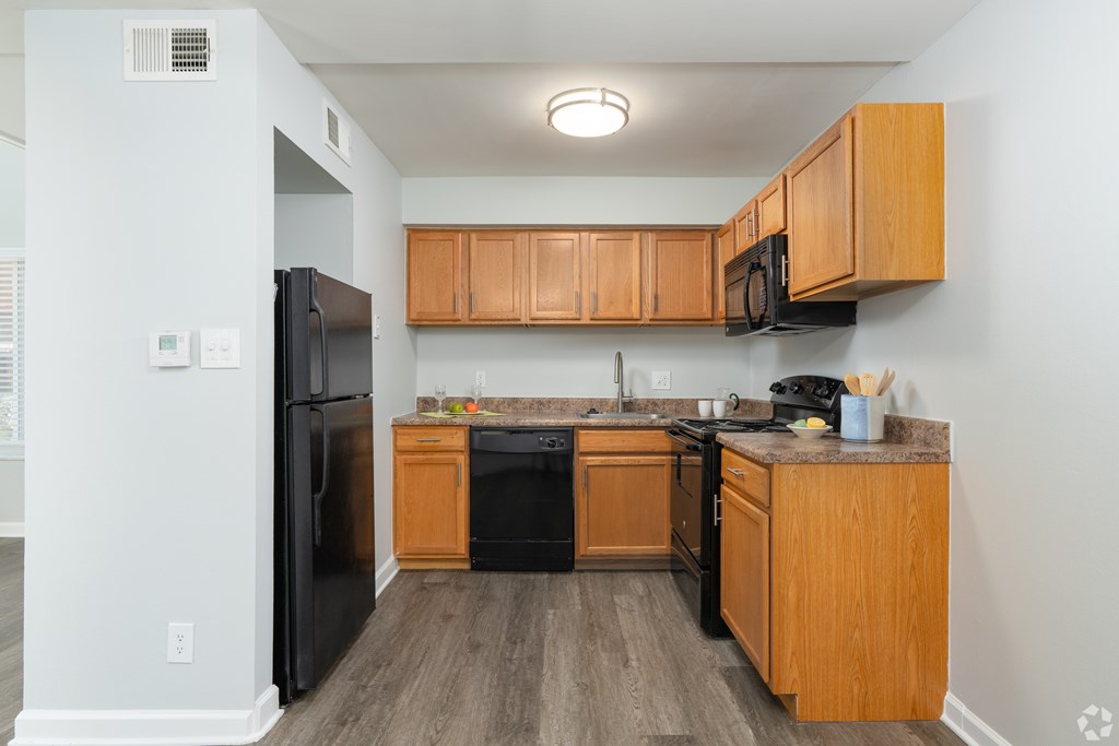 A kitchen with wooden cabinets and black appliances.