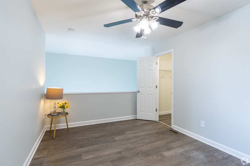 A room with a ceiling fan and a table with flowers on it.