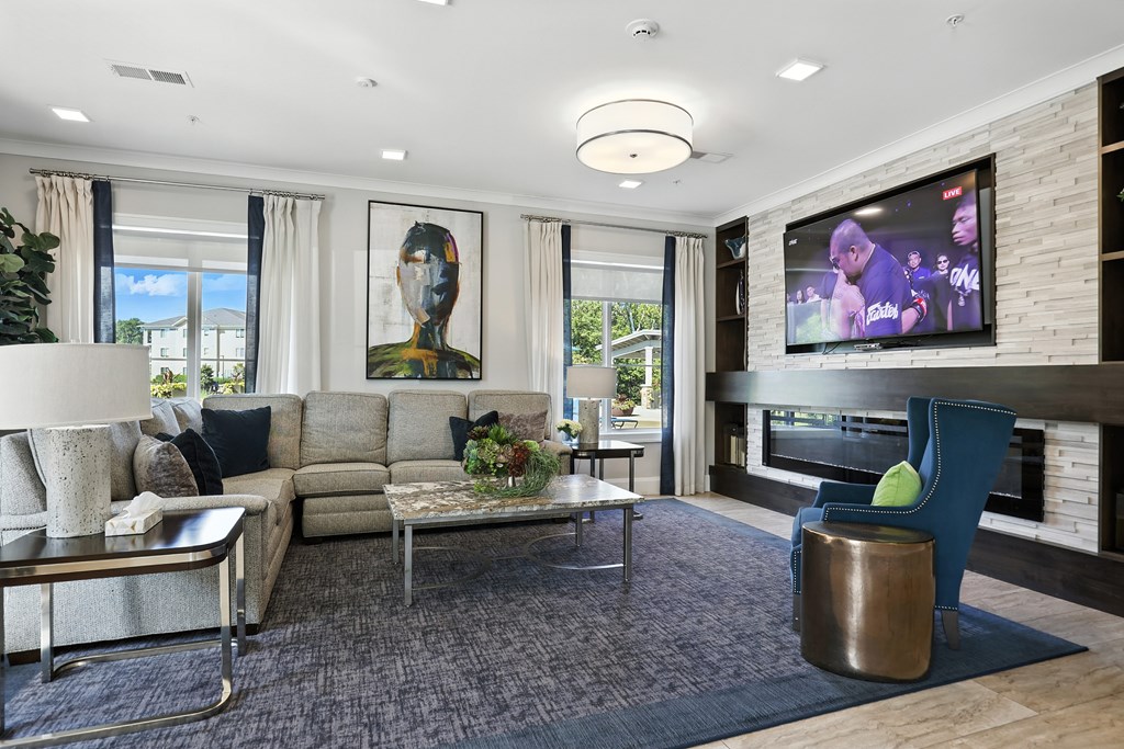 A modern living room with a large screen TV and comfortable seating.