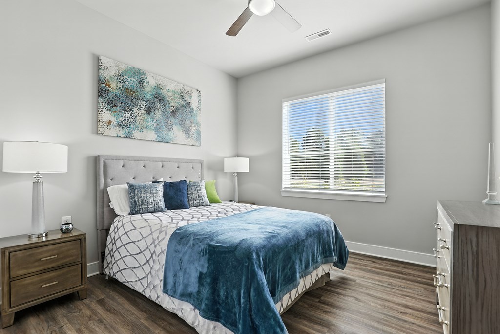 A bedroom with a bed, nightstand, and a painting on the wall.