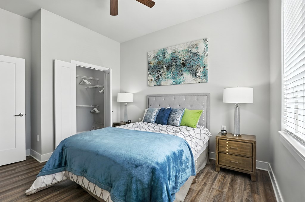 A bedroom with a blue bedspread and a ceiling fan.
