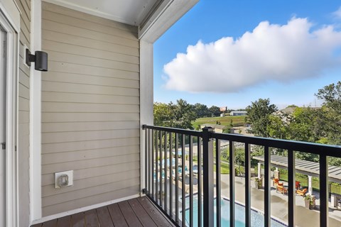 A balcony with a pool and trees in the distance.