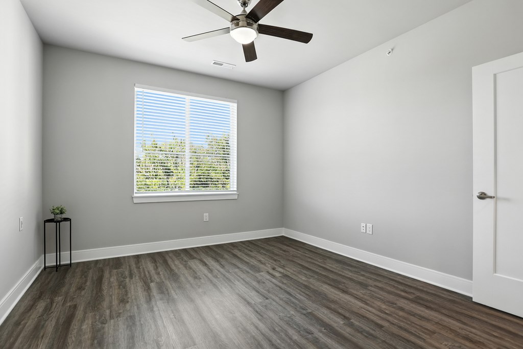 A room with a ceiling fan and a window with blinds.