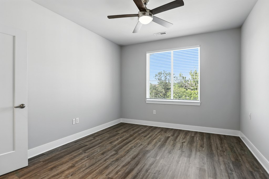A room with a ceiling fan and a window with blinds.