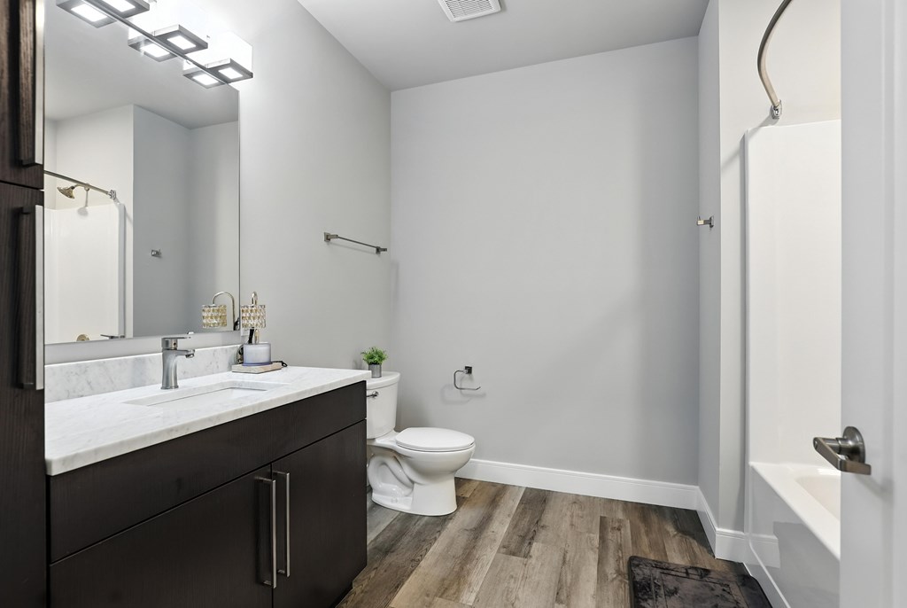 A bathroom with a toilet, sink, and mirror.