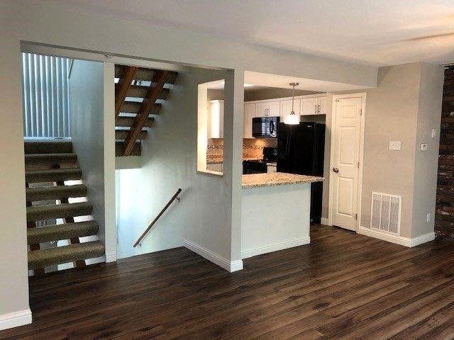 a living room with a staircase and a kitchen