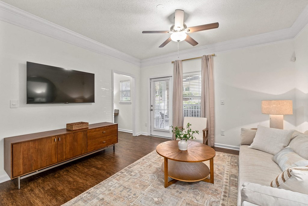 A living room with a wooden coffee table and a flat screen TV mounted on the wall.