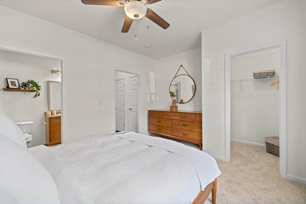 A bedroom with a large bed and a ceiling fan.