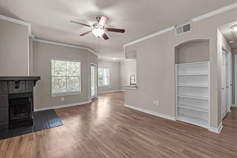 A living room with a fireplace and a ceiling fan.