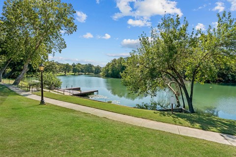 A serene park with a lake, trees, and a clear sky.