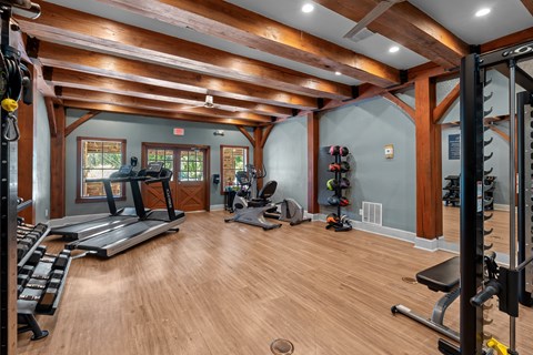 A spacious home gym with wooden floors and a variety of exercise equipment.