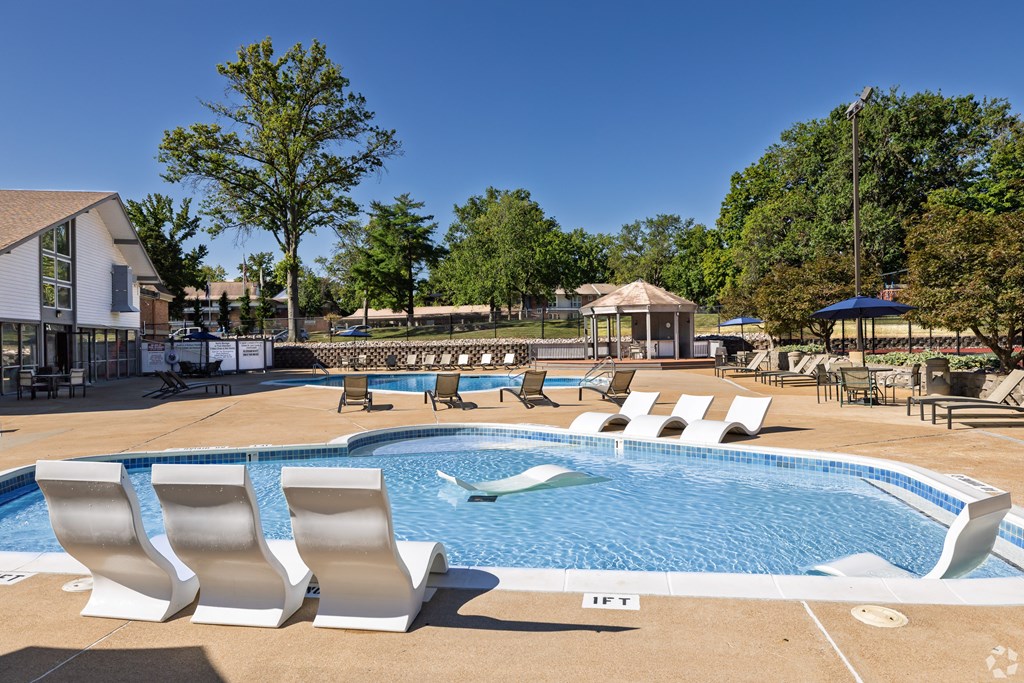 A pool with white chairs and a building in the background.