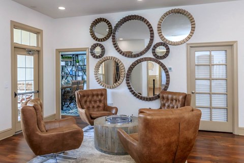 a living room with leather chairs and mirrors on the wall