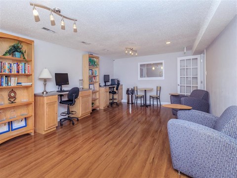 a living room with couches and chairs and a desk with a computer