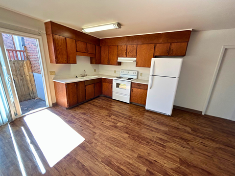 A kitchen with wooden floors and white appliances.
