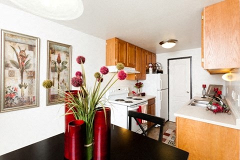 A kitchen with a black table and red vases on it.