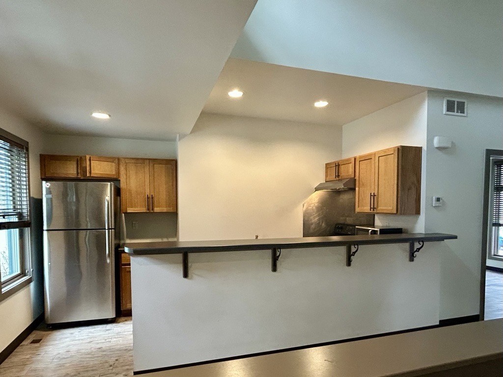 A kitchen with a stainless steel refrigerator and wooden cabinets.