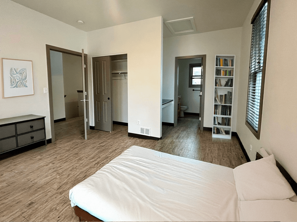 A bedroom with a bed, dresser, and bookshelf.