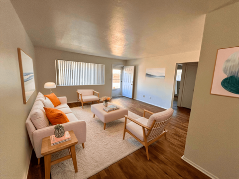 A living room with a white couch, a wooden coffee table, and a painting on the wall.