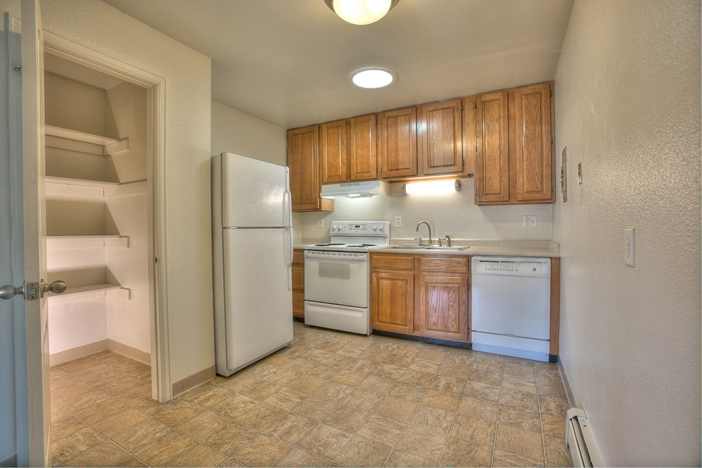 A kitchen with white appliances and wooden cabinets.